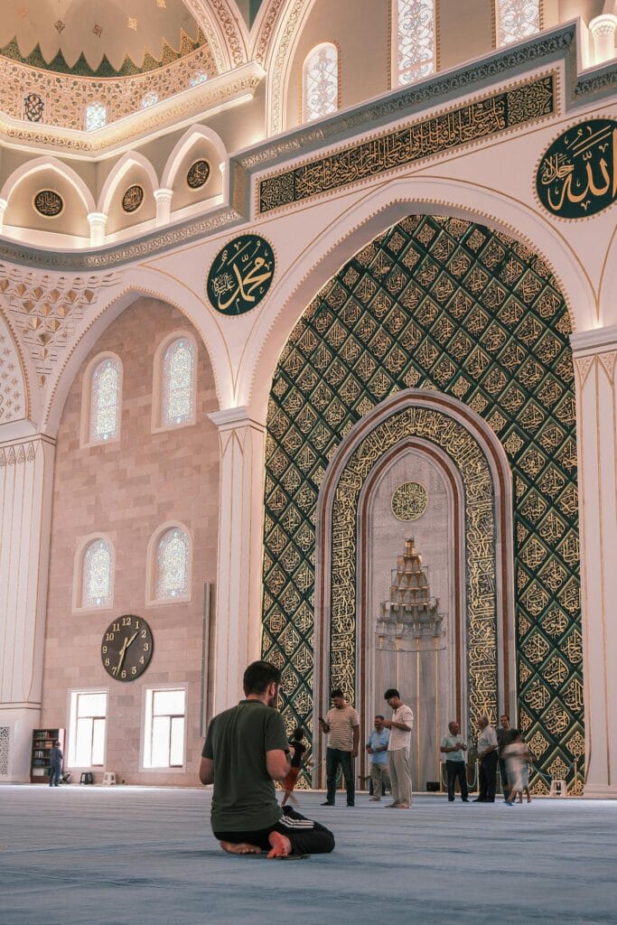 A man sitting on the floor in front of a mosque